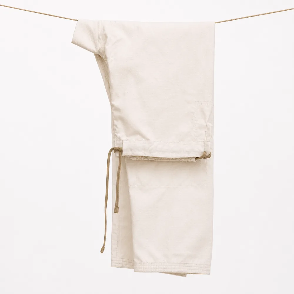 An unbleached gi folded and hanging on a line